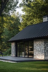 Modern stone cottage amidst lush greenery with a sleek black roof and wooden deck offers a serene retreat in nature, perfect for relaxation and enjoyment of the outdoors