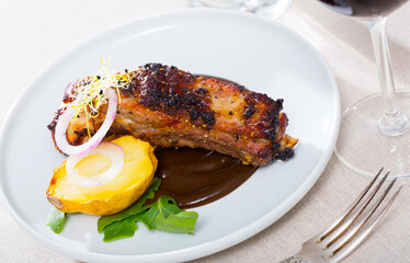 Image of tasty pork ribs baked under a mustard sauce, served with spicy sauce