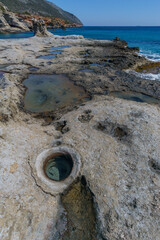 Holes of petrified tree filled with seawater at Geopark of Agios Nikolaos a Petrified Forest at mediterranean sea, Laconia, Peloponnese, Greece