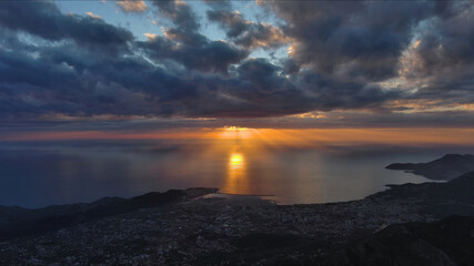Fototapeta premium Sunset over coastal town viewed from mountain with dramatic clouds