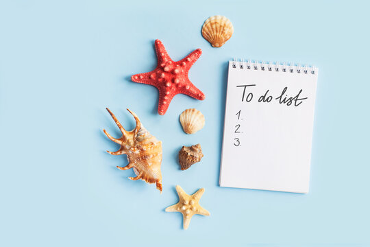To do list or blank notebook with set of starfish, sea shell on blue background. Travel, summer vacation or weekend, packing plan. lat lay, top view, copy space, place for text, minimal composition