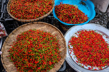 Colorful Display of Fresh Red and Green Chilies in Traditional Baskets at Local Market in Luang Prabang, Laos