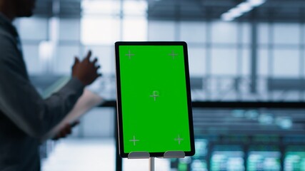Isolated screen mockup tablet in front of technicians in blurry background working in server farm, analyzing data. Close up of chroma key tablet next to coworkers examining data center, camera A