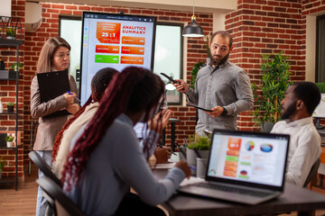 Business team analyzing marketing strategies with digital charts on led monitor. Professionals in office discussing financial analysis, utilizing modern technology for online data and information.