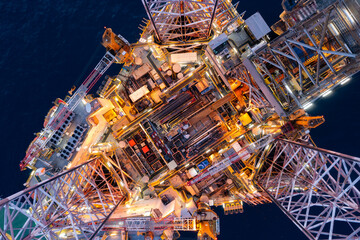 Aerial top view of silhouette offshore jack up drilling rig during sunset - oil and gas industry.