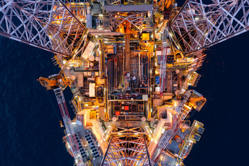 Aerial top view of silhouette offshore jack up drilling rig during sunset - oil and gas industry.