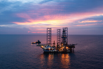 Aerial view of silhouette offshore jack up drilling rig during sunset - oil and gas industry.