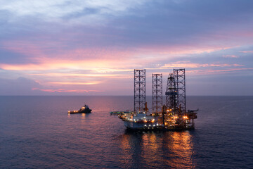 Aerial view of silhouette offshore jack up drilling rig during sunset - oil and gas industry.