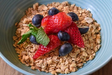 Closeup bowl of breakfast granola with fresh strawberries and blueberries