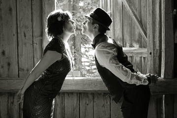 Ein Liebespaar im 20er Jahre Retro Style küssen sich vor einem Fenster