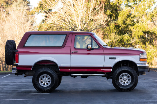 Portland, OR, USA - Dec 4, 2020 - 1994 red-white Ford Bronco XLT truck, classic American 4X4 SUV off-road vehicle exterior with with chrome bumper and oversized off-road A/T tires. High quality photo