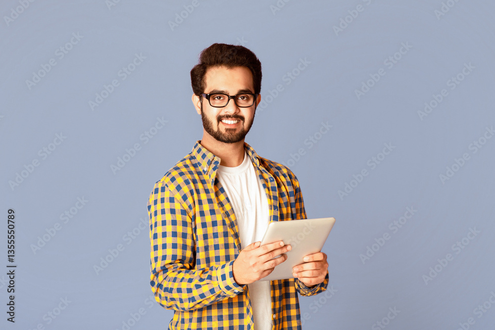 Poster online work, education or communication. funky indian man using tablet computer on violet studio bac