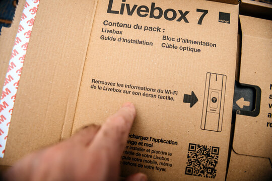 Paris, France - Feb 11, 2025: A finger points to the setup instructions on a Livebox 7 package, emphasizing the touchscreen Wi-Fi configuration features highlighted on the eco-friendly cardboard.