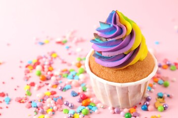 One delicious cupcake with colorful cream and sprinkles on pink background, closeup. Space for text