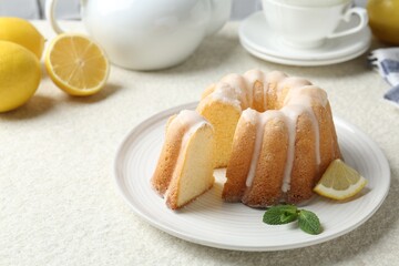 Delicious lemon cake with glaze and mint on light textured table, closeup