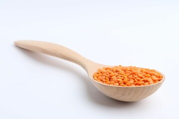 Raw lentils in wooden spoon isolated on white