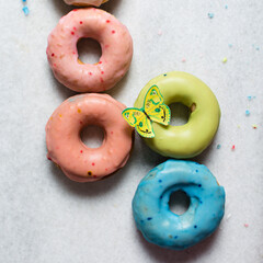 Overhead view of glazed donuts on a white countertop, top view of homemade pastel doughnuts,...