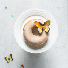 Overhead view of vanilla glazed donuts on a white countertop, top view of homemade pastel doughnuts, process of making Easter glazed doughnuts