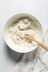 Overhead view of rolled out onion crackers dough being mixed in a white bowl, shallot cracker biscuit dough being mixed, process of making onion flatbread crackers