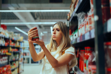 Woman Checking a Product Reading the Label in a Supermarket. Concerned customer looking for the...