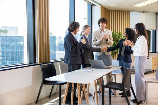 Team of diversity business people having agreement and handshake deal over new strategic strategy project on investment real estate with recognition and applause from other colleagues for partnership