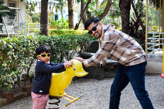 Father Son enjoying in a park and playing with a yellow colored plastic duck 