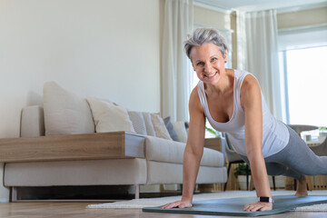 A mature woman of age with gray hair and does the plank exercise. A senior with an athletic body
