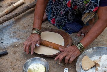 A village woman makes bread on the stove. cooking bread in clay stove , chula , makeing bread , roti , in village
