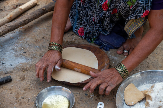 A village woman makes bread on the stove. cooking bread in clay stove , chula , makeing bread , roti , in village