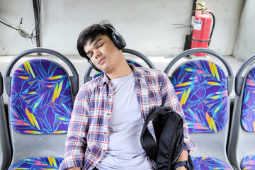Tired Man Wearing Headphones Sleeping While Commuting by Bus