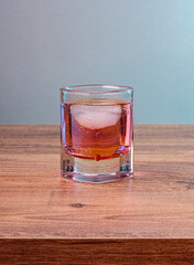 Rose liquor in shot glass with iced on wooden table. Elegant beverage presentation with suitable for drink, lifestyle or relaxation-themed projects.