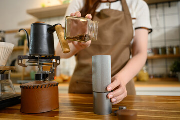Young woman grinds coffee beans and sets up a brewing station in a modern kitchen