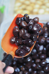 Black olives being scooped at a market stall