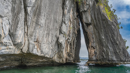 A picturesque sheer cliff above the ocean. Sparse green vegetation on steep slopes. The shore of...