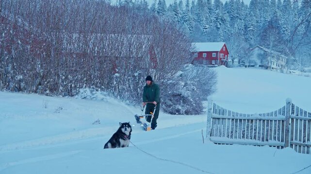 Portrait Of Man Using Snow-Blower Machine Clearing Pathway In A Rural Village. Static Shot
