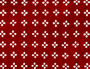 Traditional ethnic fabric in random floral and star pattern. Ethnic cloth dyed in red color. Seamless background texture.