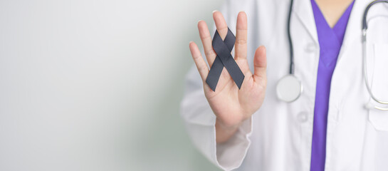 Melanoma and skin cancer, Vaccine injury awareness month and rest in peace concepts. doctor holding black Ribbon