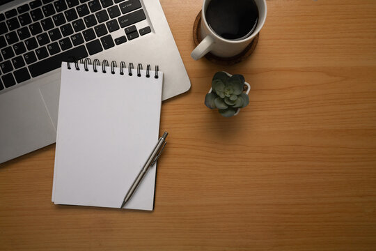 Minimalist workspace with laptop, blank notebook, a cup of black coffee, and small succulent plant