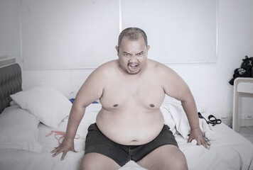 Angry Overweight Man Sitting on Bed and Shouting