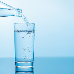 Crystal clear water being poured into a transparent glass, creating refreshing ripples and bubbles