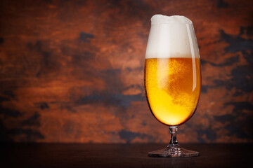 A tall glass of beer with a golden hue and frothy head