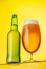A tall glass of beer with a golden hue and frothy head, on a yellow background