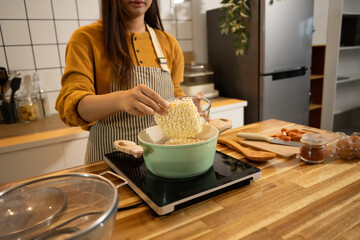 Close up shot of woman putting dried instant noodles into a boiling pot