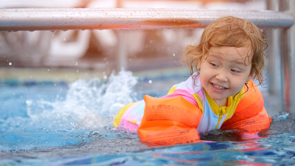 Girl paddles legs in water of pool while floaties keeping child safe