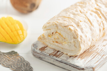 Homemade Meringue Cake Sweets Roll with Mango jam on wooden board.