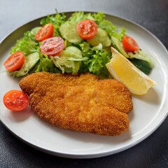 Golden Crispy Schnitzel with Fresh Salad and Lemon Wedges