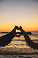 silhouette of a man and woman hands on the beach