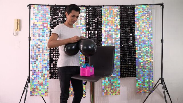 Decorator inflating balloons with electric inflator in party room