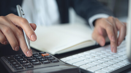 Close up business woman hand using calculator to calculate home finance and writing note, accounting on table, budget management. Doing finance, budgeting and tax calculation, monthly expenses