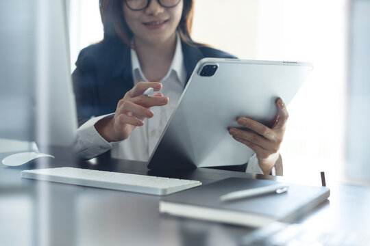 Happy asian business woman using digital tablet, working with computer on office table, internet research and networking. Entrepreneur using tablet pc for online meeting in office, closeup